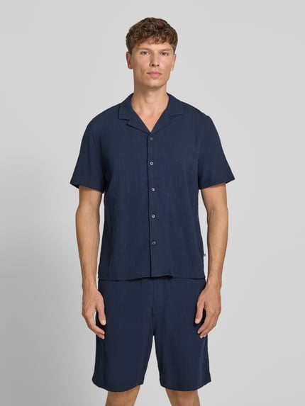 Männermodel trägt Resort Fit Freizeithemd aus reiner Baumwolle von s.Oliver RED LABEL in Dunkelblau mit glatter Struktur, Ganzkörperansicht von vorne.