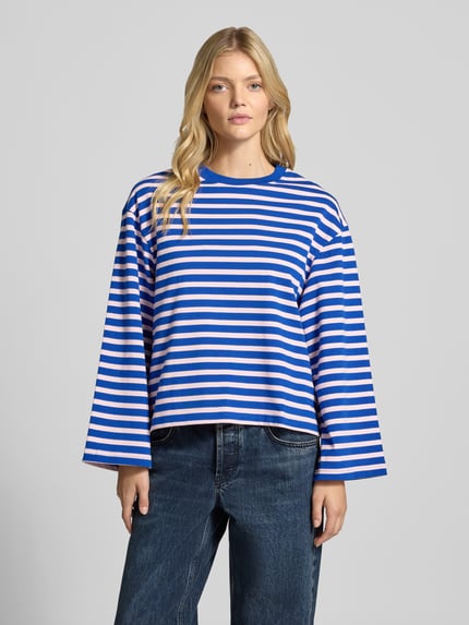 Frauenmodel trägt Longsleeve im Allover-Look mit Rundhalsausschnitt von Gina Tricot in Blau-Weiß, reine Baumwolle, Relaxed Fit, Ganzkörperansicht von vorne.