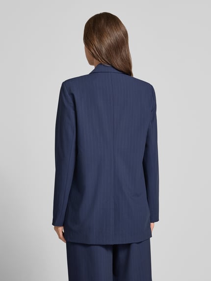 Frauenmodel trägt Blazer mit Pattentaschen Modell 'Lana' von My Essential Wardrobe, dunkelblau mit feiner Nadelstreifenstruktur, Material-Mix, Boxy Fit, Doppelknopf, Ganzkörperansicht Rückansicht.
