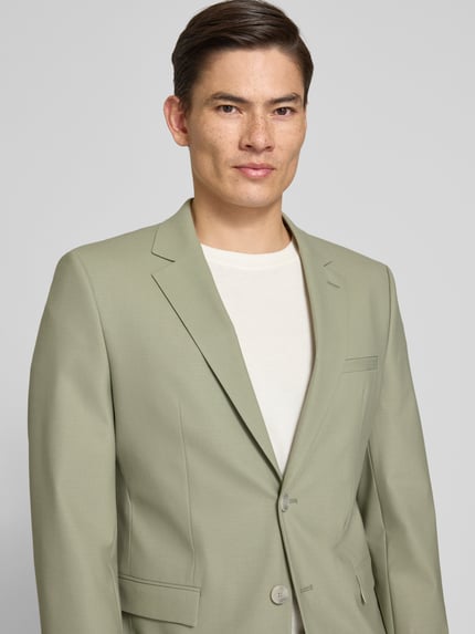 Męski model nosi Super Slim Fit Anzugsakko aus Woll-Mix Modell 'ARTI' od HUGO w jednolitym, jasnozielonym kolorze, popelina, z dwiema guzikami, krój super slim fit, detal: aplikacja z logo, marynarka z kieszeniami z patkami, perspektywa: zbliżenie na górną część ciała od przodu.