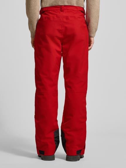 Männermodel trägt Flared Stoffhose mit Reißverschlusstaschen Modell 'KUMPULA' von LUHTA in Rot, Flared-Cut, Knopf-Reißverschluss, Ganzkörperansicht Rückansicht.