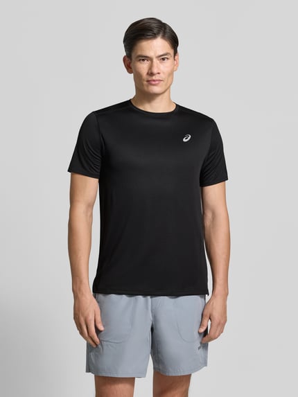 Männermodel trägt czarny Regular Fit T-Shirt mit Logo-Print von ASICS, okrągły dekolt, krótki rękaw, długość tyłu w rozmiarze M: 71 cm, męski t-shirt, Ganzkörperansicht von vorne