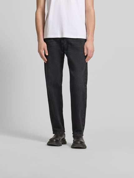 Męski model nosi Loose Fit Jeans mit Lyocell-Anteil od Diesel, mieszanka bawełny i lyocellu, krój loose fit, 5 kieszeni, label, ciemny odcień, zapięcie na guzik i zamek błyskawiczny, szerokość w rozmiarze 32/32: 43 cm, długość wewnętrzna nogawki 76 cm, widok całej sylwetki z przodu.