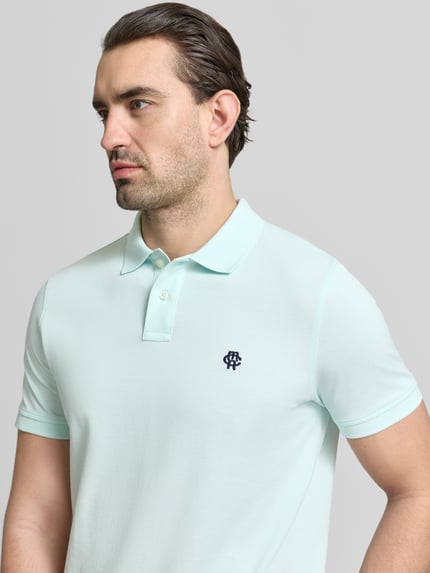 Mężczyzna model nosi Slim Fit Poloshirt mit Logo-Stitching von MCNEAL z czystej bawełny, krój slim fit, polowy kołnierzyk, jasny kolor, długość pleców w rozmiarze M: 70 cm, zbliżenie górnej części ciała z przodu.