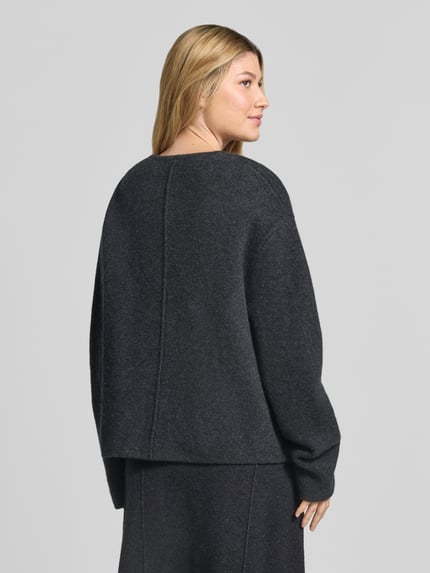 Frauenmodel trägt Strickjacke aus Wolle mit Knopfverschluss von Christian Berg Woman in Dunkelgrau, strukturierte Oberfläche, Ganzkörperansicht Rückansicht. Reine Wolle, Regular Fit, Rundhalsausschnitt, Eingrifftaschen, Rückenlänge 60 cm, Ärmellänge 46 cm.