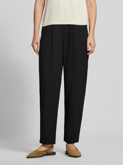 Frauenmodel trägt Relaxed Fit Anzughose mit Bundfalten Modell 'SC-SIHAM 103' von Soyaconcept in Schwarz, glatte Textur, Nahaufnahme Unterkörper, Damen Anzughose von Soyaconcept.