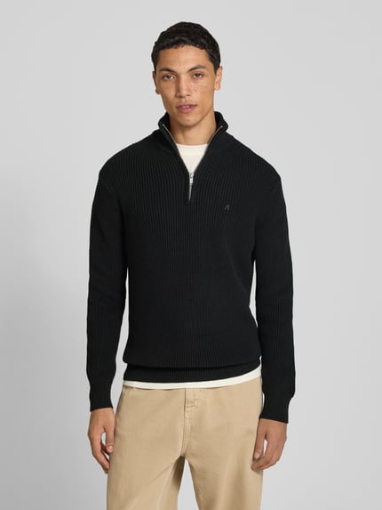 Mężczyzna nosi Slim Fit Pullover aus reiner Baumwolle in Strick-Optik od Replay, czarny, kołnierz zapinany, krój slim fit, bawełna, imitacja dzianiny, długość tyłu w rozmiarze M: 75 cm, długość rękawów w rozmiarze M: 72 cm, widok całej sylwetki z przodu.