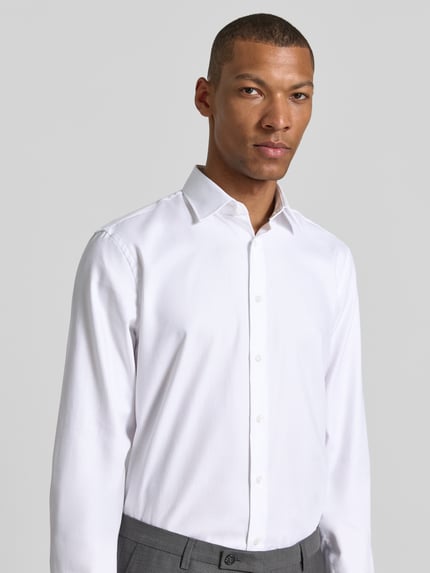 Männermodel trägt Slim Fit Business-Hemd mit Kentkragen von Jake*s aus Reine Baumwolle, Knopfleiste, Sportmanschetten, Nahaufnahme Oberkörper.