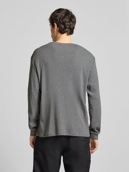 Männermodel trägt Slim Fit Longsleeve mit Logo-Patch Modell 'Waffle' von Calvin Klein Jeans im Baumwoll-Mix, Piqué, Rückenansicht Ganzkörperansicht.