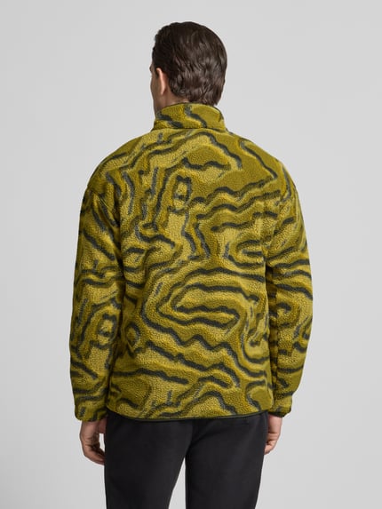 Männermodel trägt Regular Fit Pullover mit Logo-Patch von Columbia in gelb-grüner Fließ-Optik, elastische Abschlüsse, Ganzkörperansicht Rückansicht.