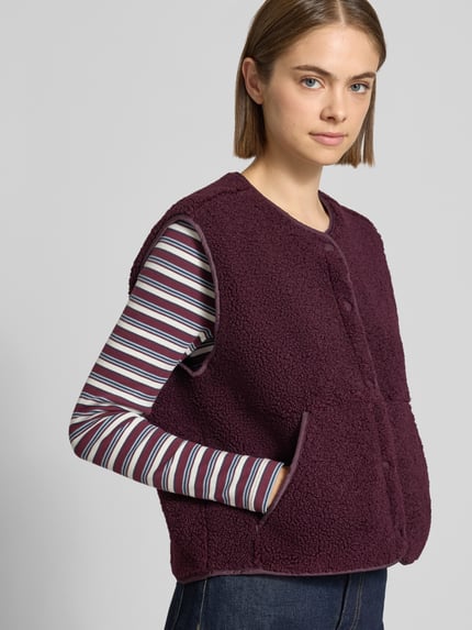 Frauenmodel trägt Regular Fit Weste aus Teddyfell Modell 'Vera' von JJXX in Dunkellila mit Rundhalsausschnitt und Eingrifftaschen, Nahaufnahme Oberkörper.