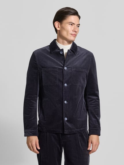 Männermodel trägt Slim Fit Hemdjacke aus Cord von MCNEAL in Dunkelblau, Knopfleiste, Brusttaschen, Baumwoll-Elasthan-Mix, Ganzkörperansicht von vorne.