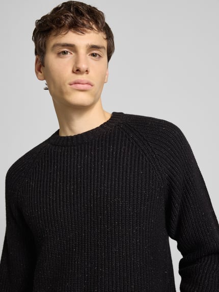 Männermodel trägt Regular Fit Strickpullover aus Baumwoll-Mix mit Woll-Anteil Modell 'LITUS' von Only & Sons in Schwarz, Nahaufnahme Oberkörper. Grobstrick, melierte Optik, Rundhals, Raglanärmel, gerippte Abschlüsse.