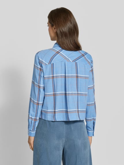 Frauenmodel trägt Regular Fit Schluppenbluse mit Brusttasche von MORE & MORE, kariertes hellblau mit braunen Streifen, Ganzkörperansicht Rückansicht
