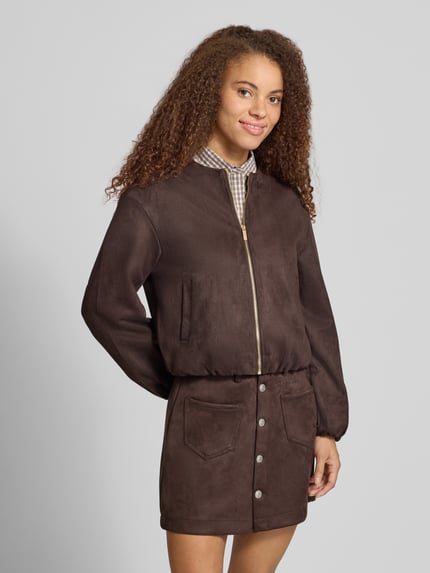 Modelka kobieca ma na sobie Regular Fit Kunstlederjacke in Velourleder-Optik Modell 'STINA' od ONLY z kolekcji damskich kurtek skórzanych, brązowa kurtka o matowej fakturze, przód zapinany na zamek, prosty krój, gładka powierzchnia, widok całej sylwetki z przodu.