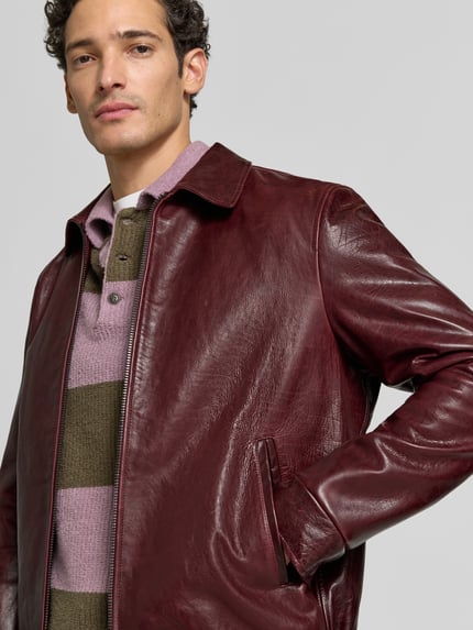 Männermodel trägt Regular Fit Jacke in Leder-Optik mit Umlegekragen von Emporio Armani in Dunkelrot, Zweiwege-Reißverschluss, Nahaufnahme Oberkörper.