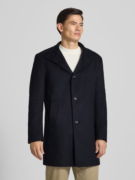 Männermodel trägt Mantel mit hohem Stehkragen Modell 'MARAN' von JOOP!, unifarben, Regular Fit, Longline, mit Knöpfen und Seitentaschen, Ganzkörperansicht von vorne.