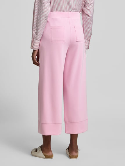 Frauenmodel trägt Wide Leg Sweatpants mit Eingrifftaschen von Rich & Royal in Rosa, Modal-Mix mit Stretch, elastischer Bund, Ganzkörperansicht Rückansicht.