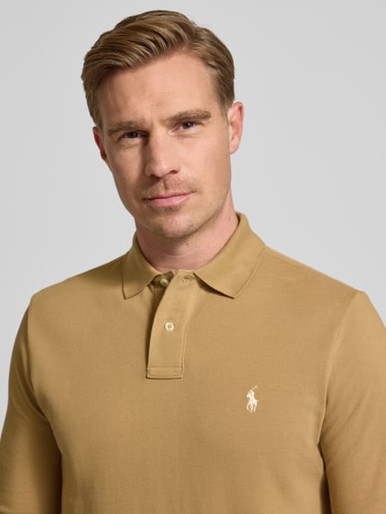 Männermodel trägt Poloshirt mit Label-Stitching von Polo Ralph Lauren in Beige, reine Baumwolle, gerippte Ärmel, Nahaufnahme Oberkörper.