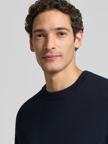 Männermodel trägt Pullover mit Rippbündchen von Selected Homme, unifarben, Strickstruktur, Rundhals, dunkelblau, Nahaufnahme Oberkörper.