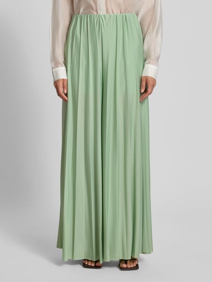 Vrouwenmodel draagt stoffen broek van satijn in pastelgroen met plissévouwen, wide leg fit, model 'Samantha' van GUIDO MARIA KRETSCHMER WOMAN, elastische band, binnenbeenlengte maat 36: 73 cm, bandwijdte maat 36: 34 cm, voorkant tot enkel, close-up onderlichaam