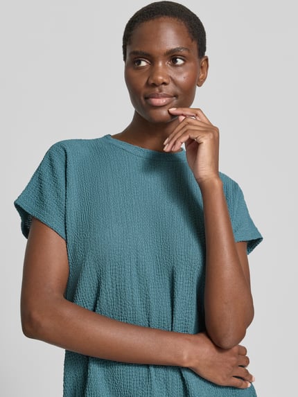 Frauenmodel trägt T-Shirt mit Strukturmuster und Rundhalsausschnitt von Christian Berg Woman in Blau, Material-Mix mit Stretch, Nahaufnahme Oberkörper.