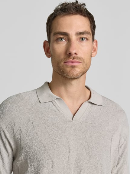 Männermodel trägt Relaxed Fit Poloshirt aus reiner Baumwolle Modell 'ASURFO' von BOSS Orange in Optik: Unifarben, Struktur, Label-Applikation, Polokragen, V-Ausschnitt, Kurzarm, Materialverarbeitung: Frottee, Nahaufnahme Oberkörper.