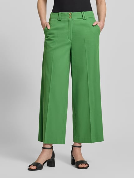 Frauenmodel trägt Wide Leg Hose aus Viskose-Mix mit Bügelfalten von More & More in Grün, glatte Textur, Mittellang, Nahaufnahme Unterkörper. Damen Hose Viskose-Mix mit Baumwoll-Anteil, Knopf- und Reißverschluss, Bundweite 39 cm, Innenbeinlänge 66 cm.