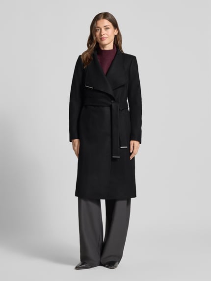 Vrouwenmodel draagt Mantel met Bindegürtel Modell 'ROSE' van Ted Baker in zwart, slanke fit, staande kraag, knoopsluiting, labeldetail, bindriem, glad oppervlak, lange mouwen, geheel lichaamsaanzicht van voren.
