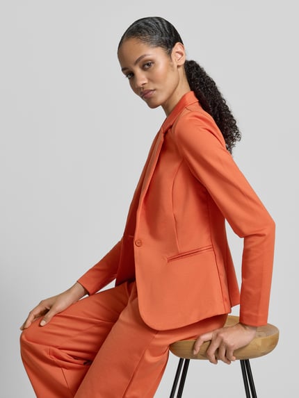 Frauenmodel trägt Blazer mit Reverskragen Modell 'KATE' von ICHI in Orange, Material-Mix mit Viskose-Anteil, Regular-Fit, Knopfverschluss, Paspeltaschen, Ganzkörperansicht von vorne, Kontext: Rückenlänge 63 cm, Brustweite 39 cm, Ärmellänge 64 cm bei Größe S.