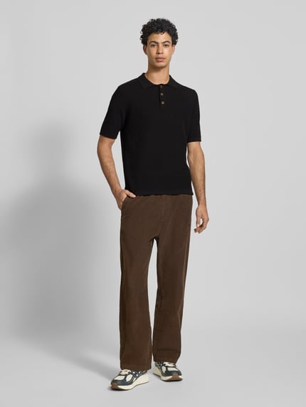 Männermodel trägt Regular Fit Poloshirt aus reiner Baumwolle Modell 'ERIC' von Only & Sons, Optik: Unifarben, Struktur, Polokragen, Kurzarm, Materialverarbeitung: Strick, Farbe: Schwarz, Ganzkörperansicht von vorne.
