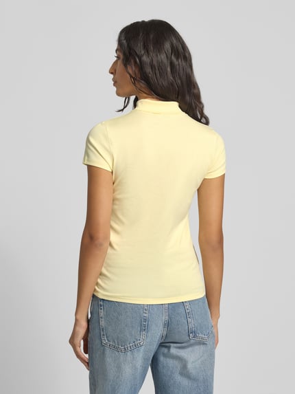 Frauenmodel trägt Slim Fit T-Shirt mit Polokragen von Marc Cain aus Baumwoll-Elasthan-Mix, Rückenlänge 58 cm, Label-Detail, Ganzkörperansicht Rückansicht.