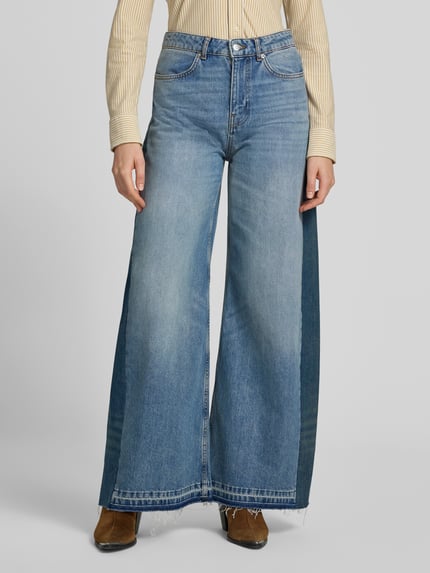 Frauenmodel trägt Wide Leg Jeans mit Fransensaum Modell 'MISLAV' von ba&sh in Blau, reine Baumwolle, Eingrifftaschen, Ganzkörperansicht von vorne.