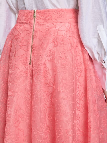 Frauenmodel trägt Midirock mit floralem Allover-Stitching Modell 'Krizie' von Ted Baker in Rosa, A-Linie, Nahaufnahme Oberkörper.