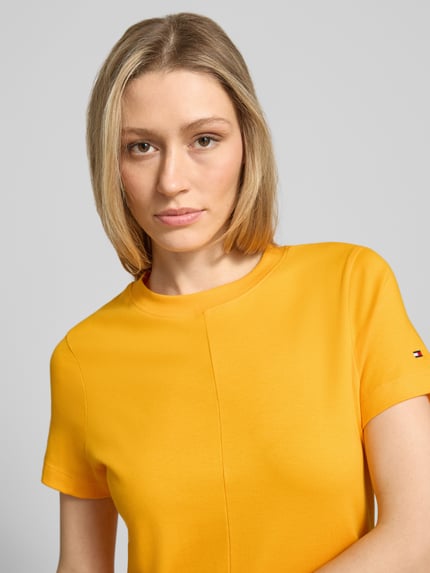 Frauenmodel trägt Midikleid aus reiner Baumwolle von Tommy Hilfiger, Optik: Unifarben, Passform: Regular-Fit, Rundhals, Logo-Stitching, Ärmelform: Kurzarm, Materialverarbeitung: Interlock, Nahaufnahme Oberkörper.