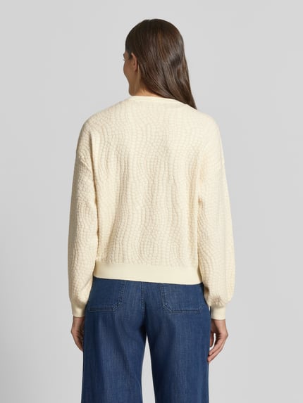 Frauenmodel trägt cremefarbenen Regular Fit Pullover aus Viskose-Mix Modell 'NANCY' von VERO MODA, strukturierte Oberfläche, Ganzkörperansicht Rückansicht. Damen Pullover von VERO MODA.