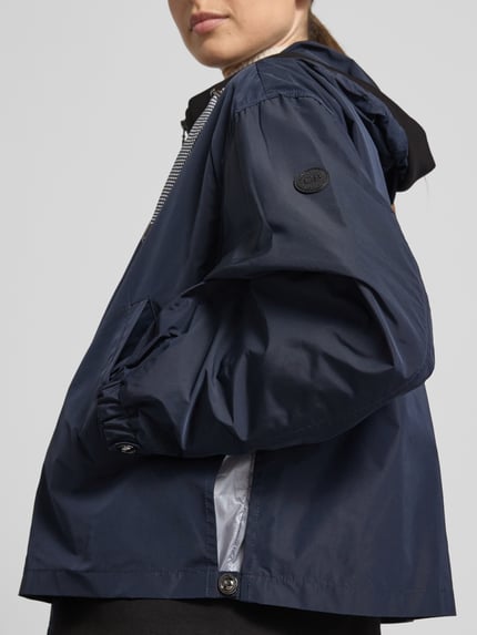 Frauenmodel trägt Jacke mit Zweiwege-Reißverschluss von Gil Bret in Dunkelblau, Relaxed-Fit, Kapuze mit Tunnelzug, Eingrifftaschen, Nahaufnahme Oberkörper. Rückenlänge 59 cm, Schulterbreite 52 cm, Brustweite 57 cm, Ärmellänge 57 cm bei Größe 36.