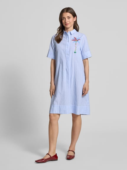Frauenmodel trägt Knielanges Hemdblusenkleid mit Motiv-Print von Milano Italy aus Reine Baumwolle, Gerader-Schnitt, Knielänge, Knopfleiste, 1/2-Arm, hellblau mit buntem Motiv-Print, Ganzkörperansicht von vorne.