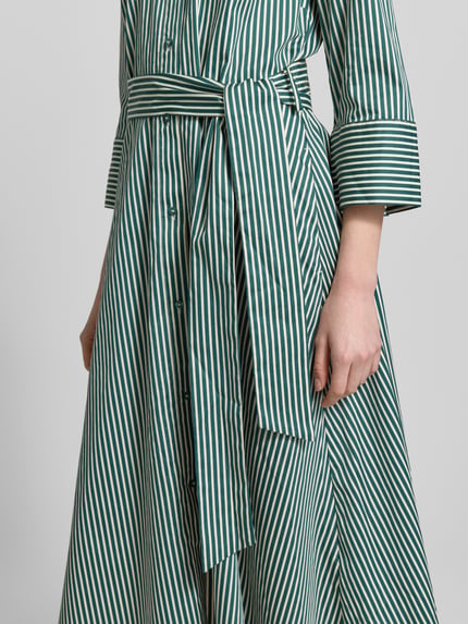 Vrouwenmodel draagt midi-jurk met overhemdkraag van Christian Berg Woman van puur katoen, getailleerde pasvorm, 3/4-mouw, knoopsluiting, afneembare tailleband, ruglengte maat 36: 123 cm, borstwijdte 48 cm, mouwlengte 48 cm, detailopname taille.