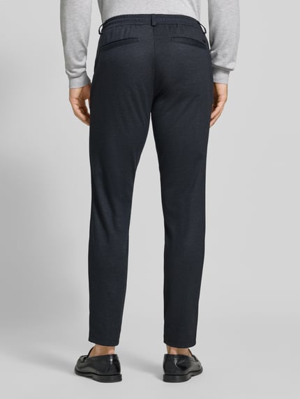 Männermodel trägt dunkelblaue Tapered Fit Jogpants mit Viskose-Anteil Modell 'Phil' von Brax, Herren Weite Hose, Ganzkörperansicht Rückansicht.