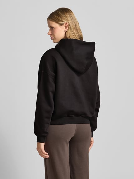 Frauenmodel trägt Hoodie mit Motiv-Stitching und Känguru-Tasche von REVIEW, Farbton Schwarz, Baumwoll-Mix, Regular-Fit, Ganzkörperansicht Rückansicht.
