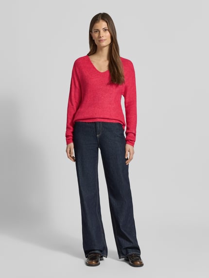 Kobiece modelka nosi sweter Regular Fit Pullover mit V-Ausschnitt Modell 'CREWLEFILE' od Vero Moda, jednokolorowy, krój regular fit, dekolt w serek, długi rękaw, prążkowana dzianina, widok całej sylwetki z przodu.