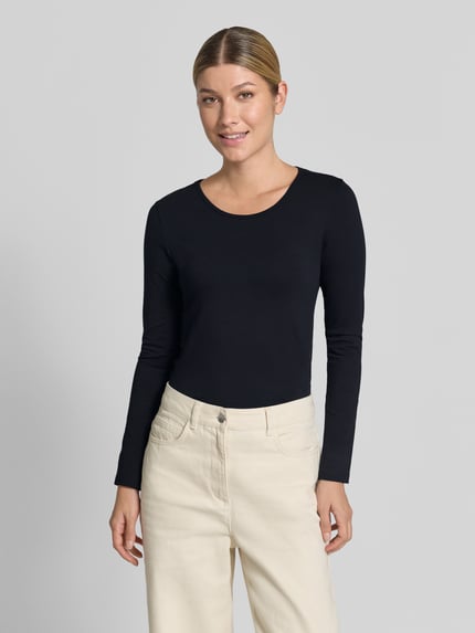Frauenmodel trägt Longsleeve mit Rundhalsausschnitt von ZABAIONE, taillierter Schnitt, schwarz, glatte Textur, Ganzkörperansicht von vorne. Baumwoll-Elasthan-Mix, Rückenlänge bei Größe S: 55 cm.