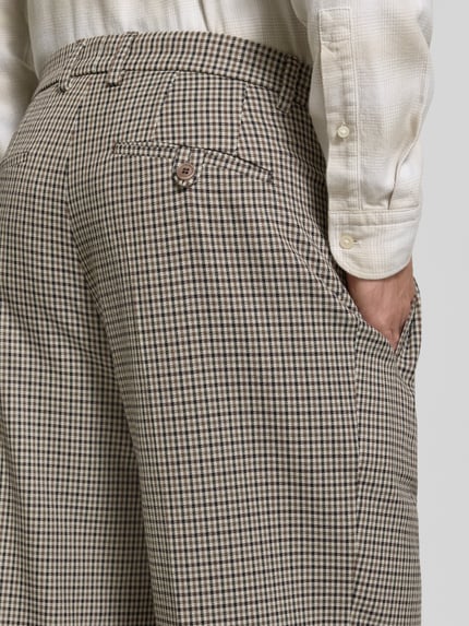 Männermodel trägt Hose mit Gesäßleistentaschen Modell 'WYACO' von DRYKORN, feines Karomuster, Beige und Braun, Nahaufnahme Rückansicht. Bundweite und Innenbeinlänge laut Kontext.