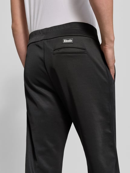 Männermodel trägt Sweatpants mit Stretch-Anteil von RHUDE in Schwarz, elastischer Bund, Ziernähte, Detailaufnahme Rückansicht.