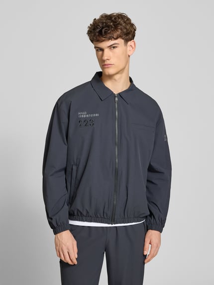 Męski model nosi Regular Fit Hemdjacke mit Logo Modell 'HALO MOVE' od HALO, wykładany kołnierz, zamek błyskawiczny, długość tyłu 66 cm, długość rękawów 61 cm, ciemnoszary, gładka faktura, Ganzkörperansicht z przodu.