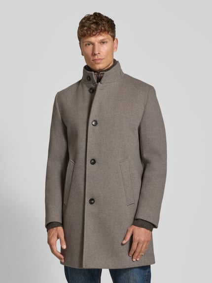 Męski model nosi Mantel mit Stehkragen und Eingrifftaschen od bugatti, beżowy, krój regular fit, zapięcie na guziki, widoczne kieszenie, przód, zdjęcie całego ciała, długość pleców w rozmiarze 50: 92 cm, szerokość ramion w rozmiarze 50: 45 cm, szerokość klatki piersiowej w rozmiarze 50: 55 cm, długość rękawa w rozmiarze 50: 62 cm. Ganzkörperansicht von vorne.