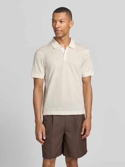 Męski model nosi Modern Fit koszulkę polo z fakturowanym wzorem model 'Roberto' od JOOP! Collection z bawełny, kołnierzyk polo, krótka listwa guzikowa, detal z logo, długość tyłu w rozmiarze M: 68 cm, widok całej sylwetki z przodu.