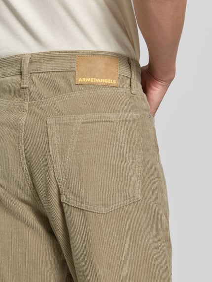 Männermodel trägt Wide Leg Cordhose aus Baumwoll-Mix Modell 'JAAMEO' von ARMEDANGELS in Beige, Herren Weite Hose, Nahaufnahme Rückansicht.