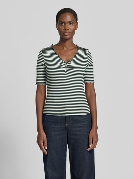 Modelka nosi t-shirt z falistym brzegiem od Zero, krój slim fit, dekolt w serek, mieszanka bawełny (bio) i elastanu, długość tyłu w rozmiarze 36: 52 cm, biało-zielone paski, widok całej sylwetki z przodu.